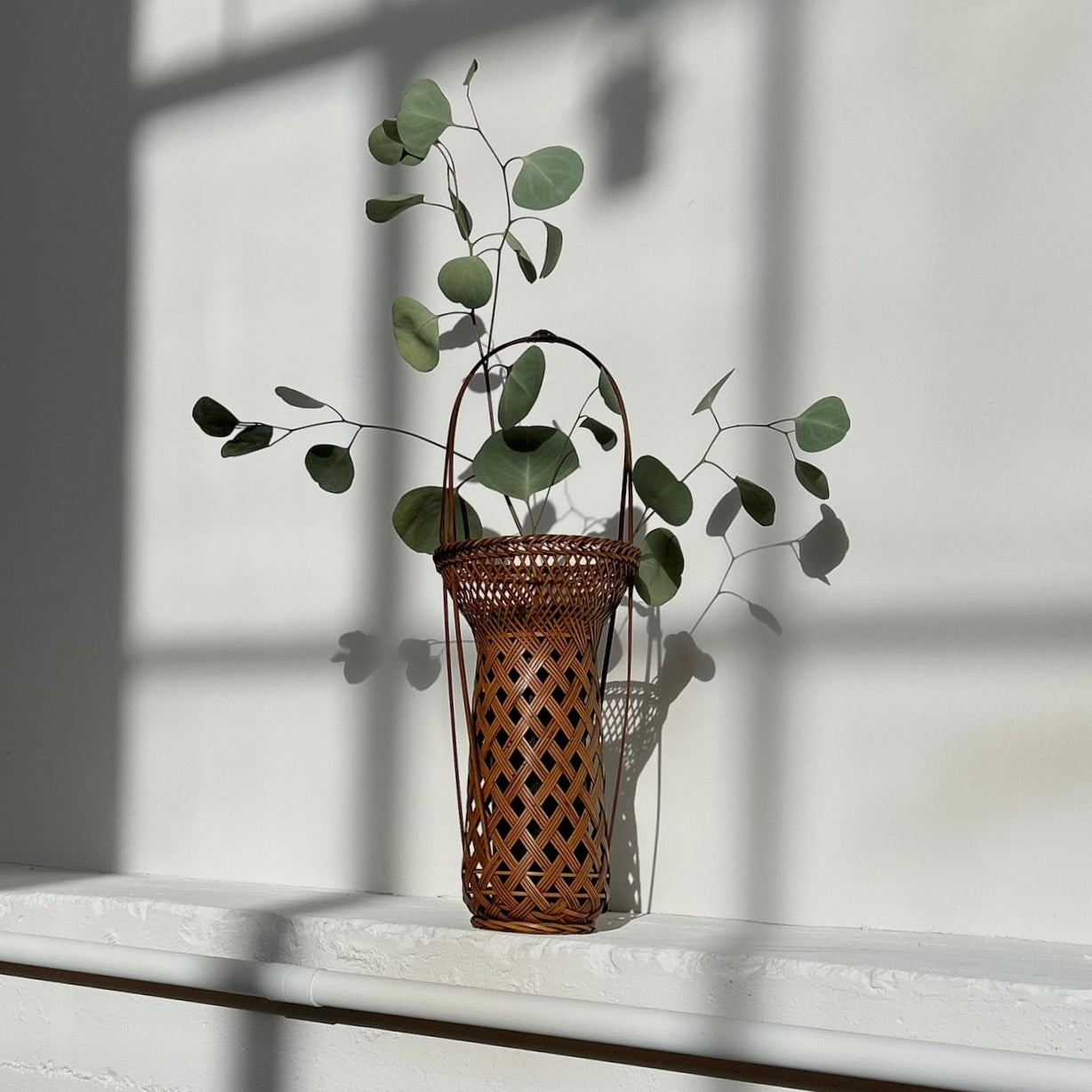 A vintage Japanese Ikebana (flower arrangement) basket with handle. Woven by hand in Japan from caramel colored bamboo. Circa 1950.