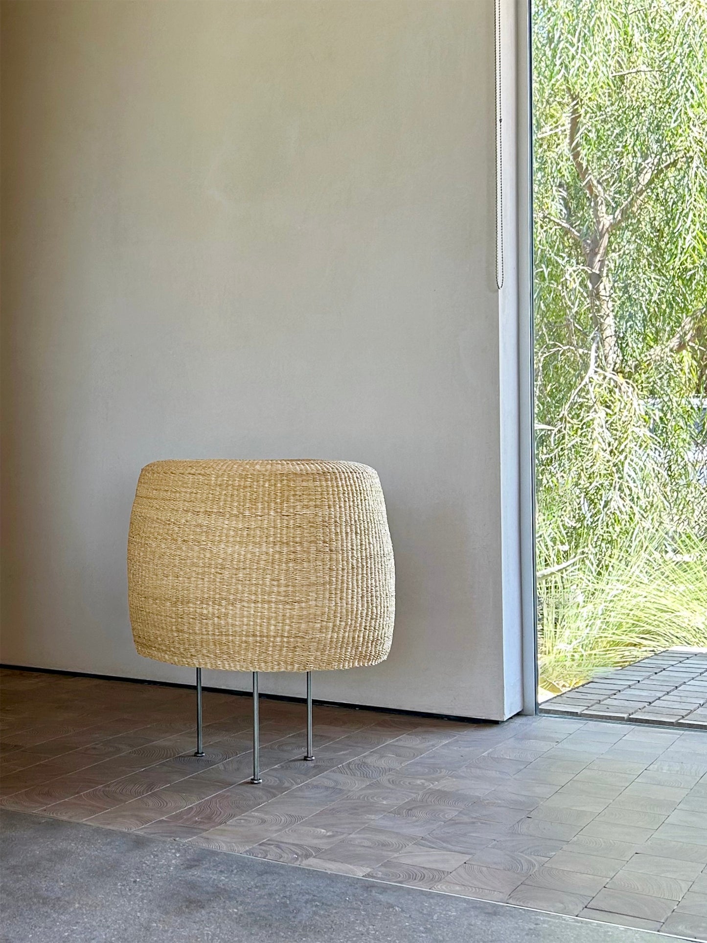 Woven floor lamp with steel tripod base in a modern indoor setting