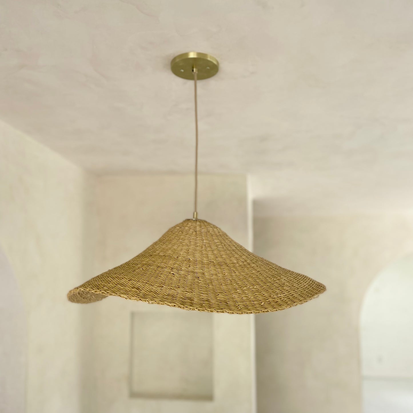 The Landslide pendant lights are made with natural colored, sustainable elephant grass in northern Ghana. Hand woven as a shallow cone and shaped into undulating waves, these lights are beautiful in bedrooms as well as living spaces.