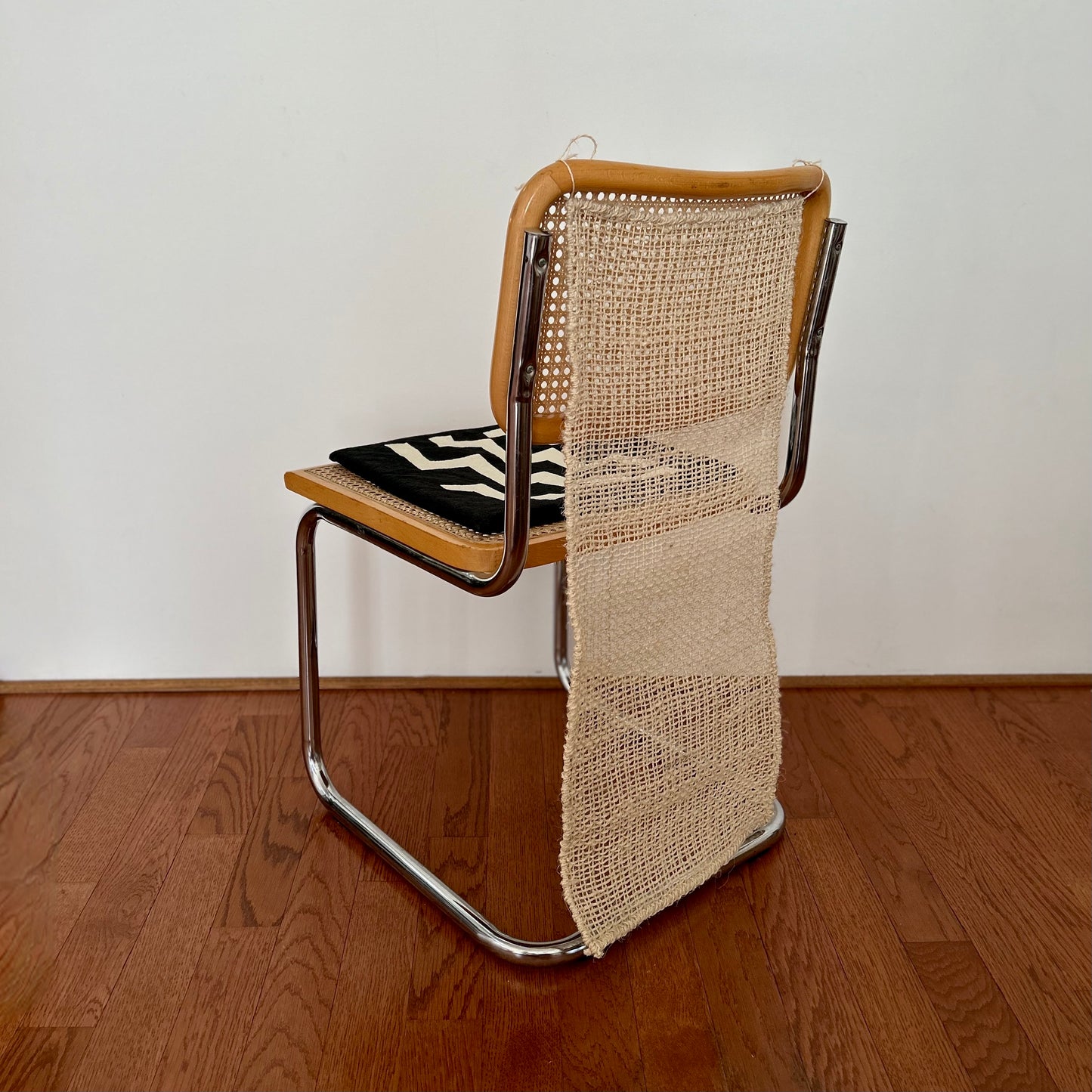The Cortina Silla is a natural colored, handwoven textile hanging. It's made in Oaxaca, Mexico, from the leftover maguey leaves from mezcal production. Shown hanging from the back of a chair, as it's designed to do, by ties at the top corners.