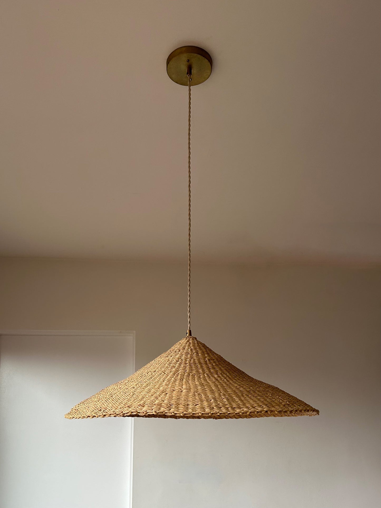 The Sunhat pendant light is a shallow cone shape, handwoven from natural colored, sustainable elephant grass in northern Ghana. With its classic shape this pendant is ideal for any living space.