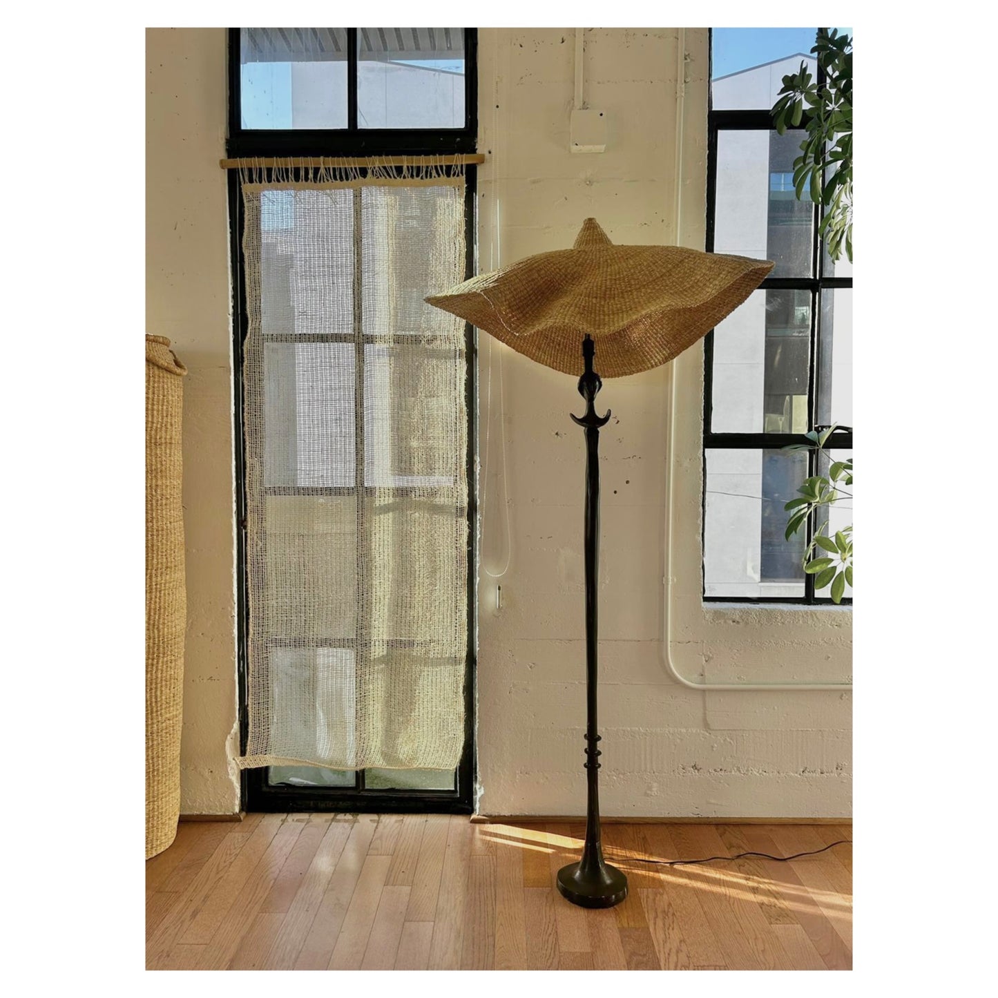 Our Cortina Puerta is a sheer handwoven textile hanging, 76” high by 27” wide. Shown here against a glass door with a floor lamp. These natural colored curtains make beautiful room dividers, window coverings or wall hangings.