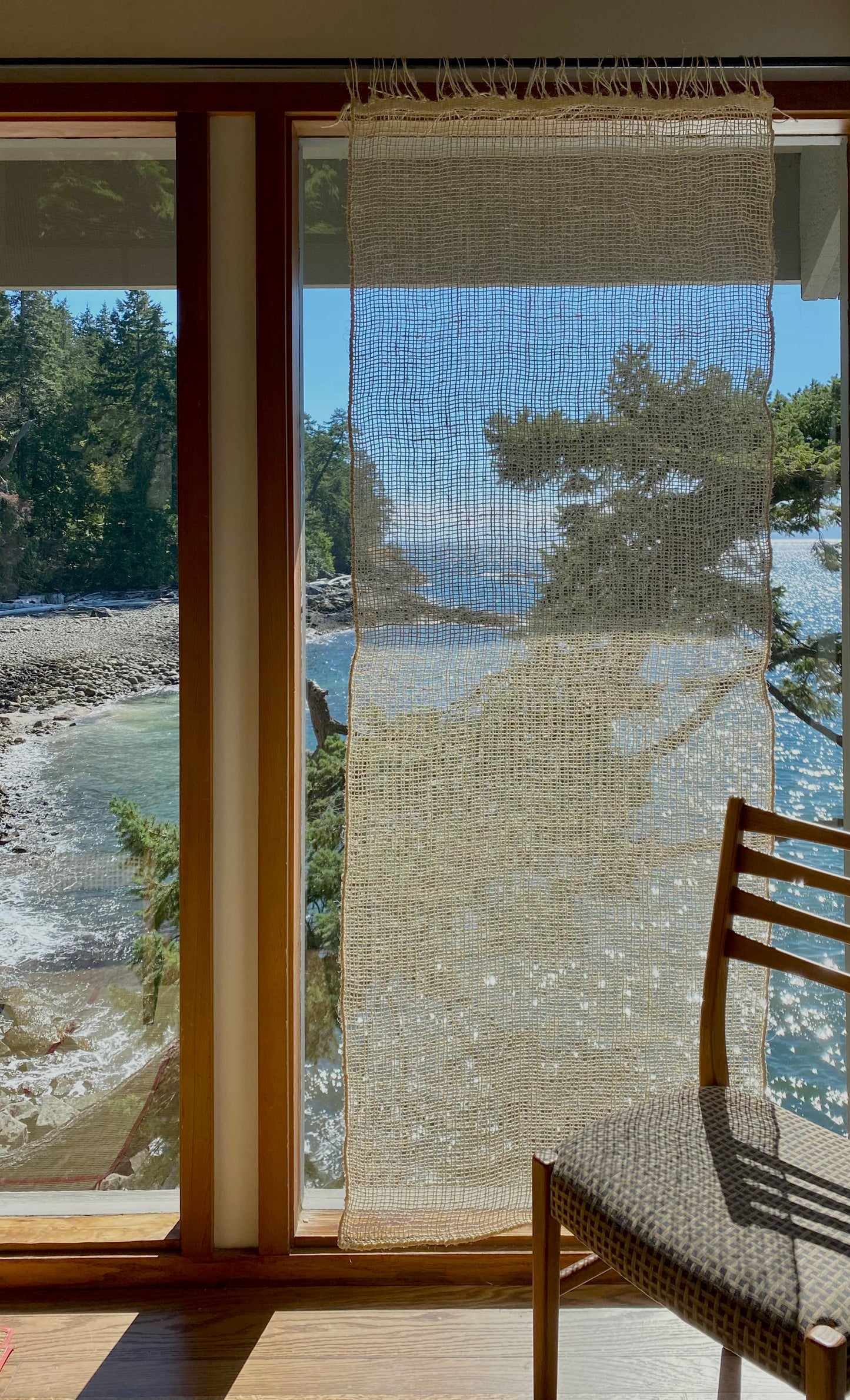 Shown against a wall - Our Cortina Puerta is a sheer handwoven textile hanging, 76” high by 27” wide. It's made in Oaxaca, Mexico, from the leftover maguey leaves from mezcal production. These natural colored curtains make beautiful room dividers, window coverings or wall hangings.