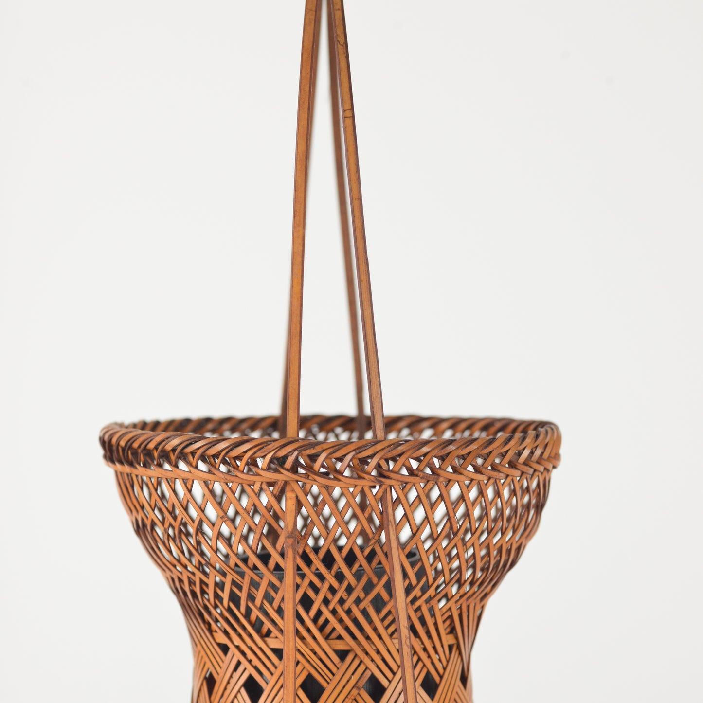 Close up of a vintage Japanese Ikebana (flower arrangement) basket with handle. Woven by hand in Japan from caramel colored bamboo. Circa 1950.