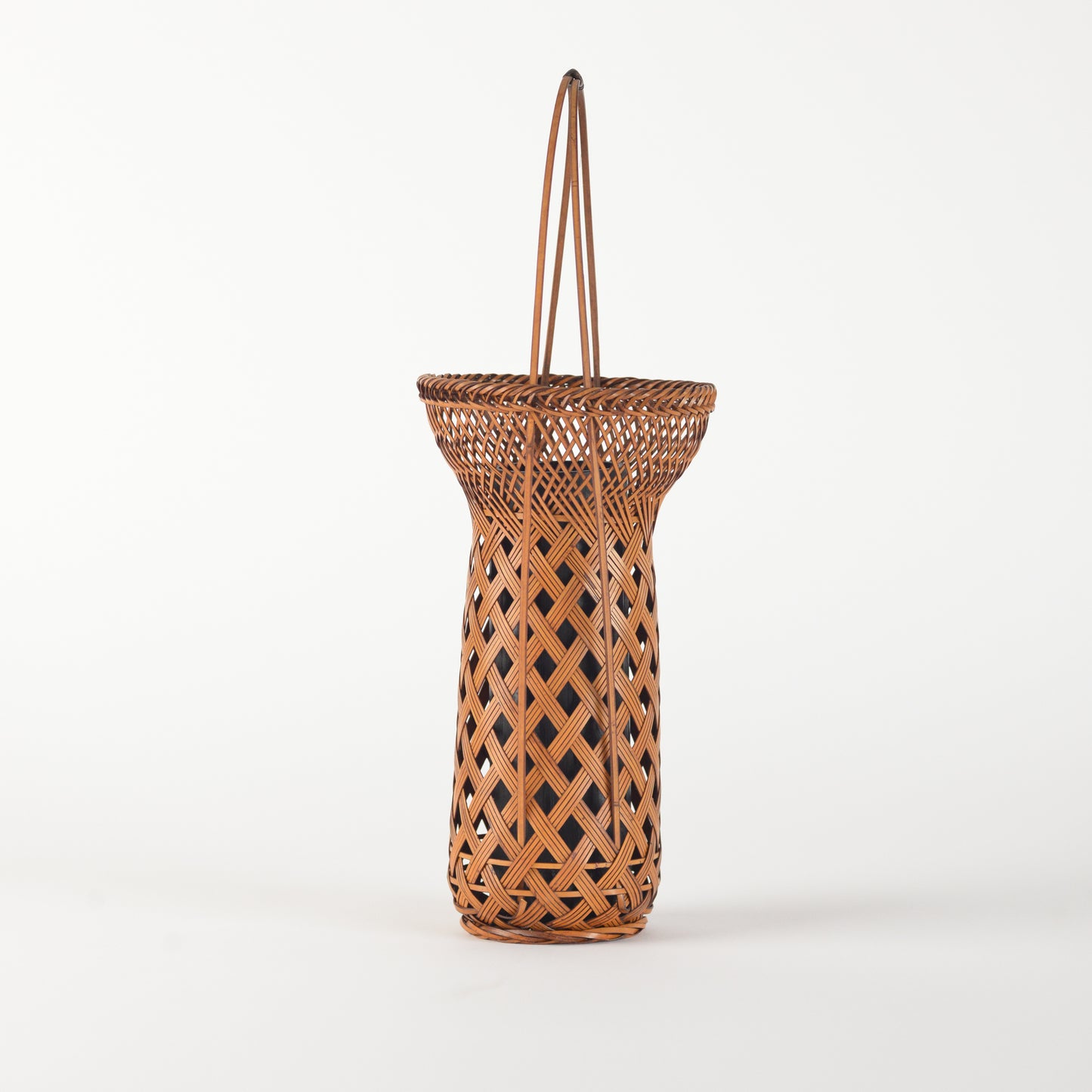 A vintage Japanese Ikebana (flower arrangement) basket with handle. Woven by hand in Japan from caramel colored bamboo. Circa 1950.