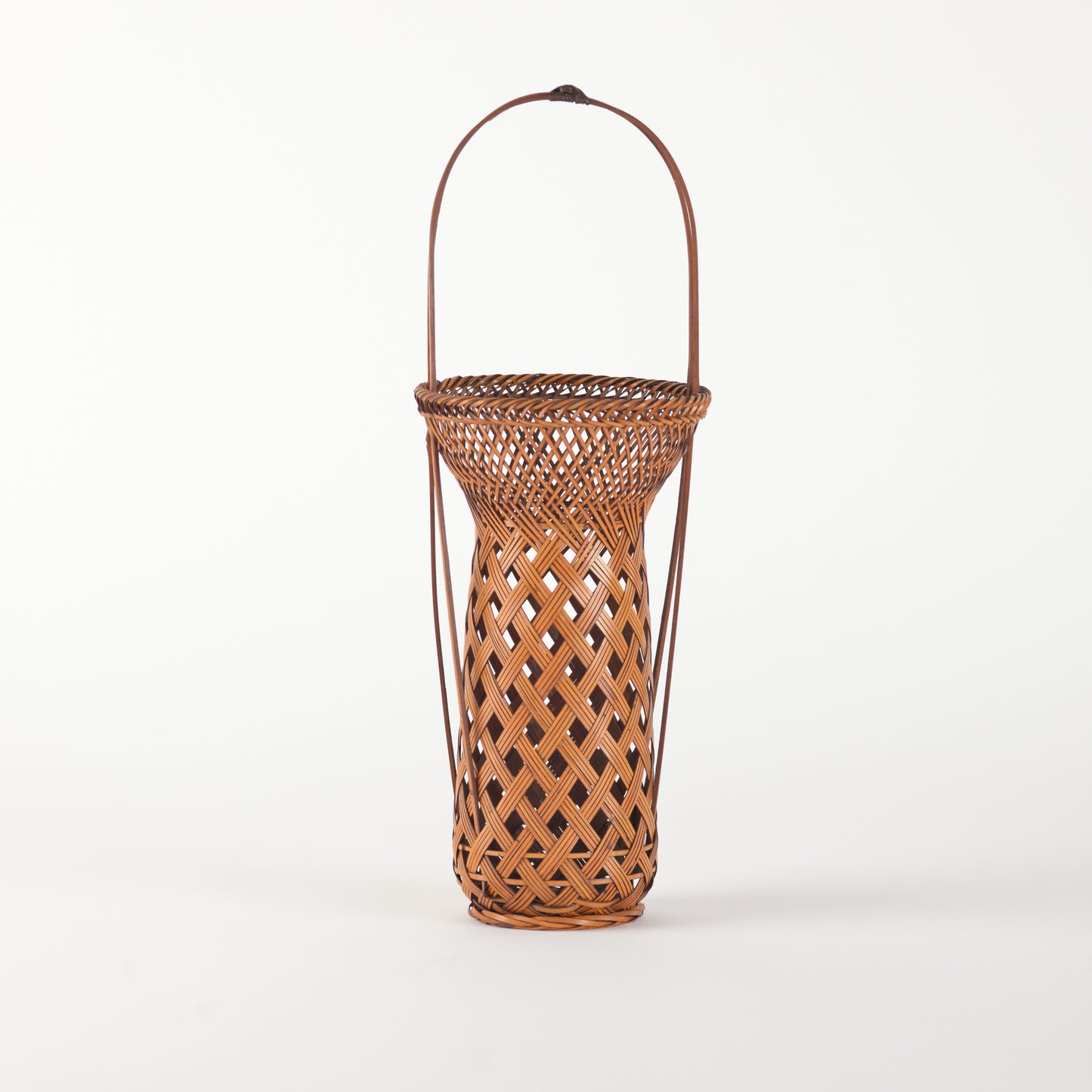 A vintage Japanese Ikebana (flower arrangement) basket with handle. Woven by hand in Japan from caramel colored bamboo. Circa 1950.