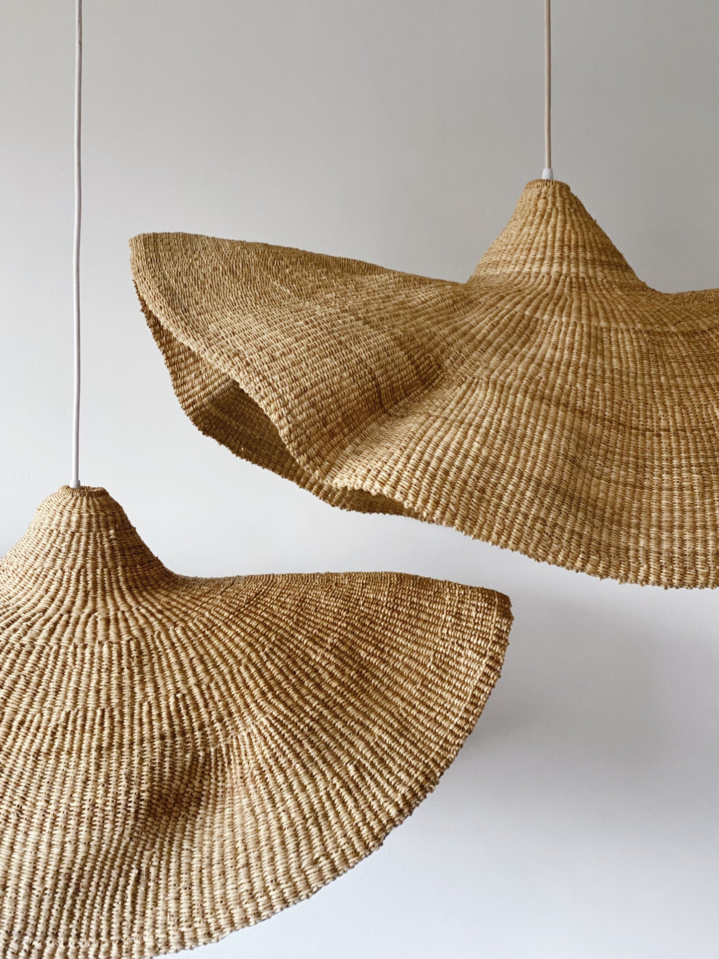 Two woven light shades, handwoven from sustainable elephant grass in Ghana. Their wide and floating shape are striking in any living space, especially in bedrooms or over dining tables.