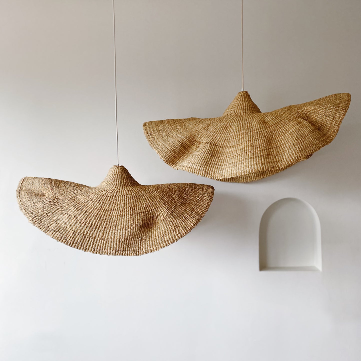 Two Peaked Fawn light shades, handwoven from sustainable elephant grass in Ghana. Their wide and floating shape are striking in any living space, especially in bedrooms or over dining tables.
