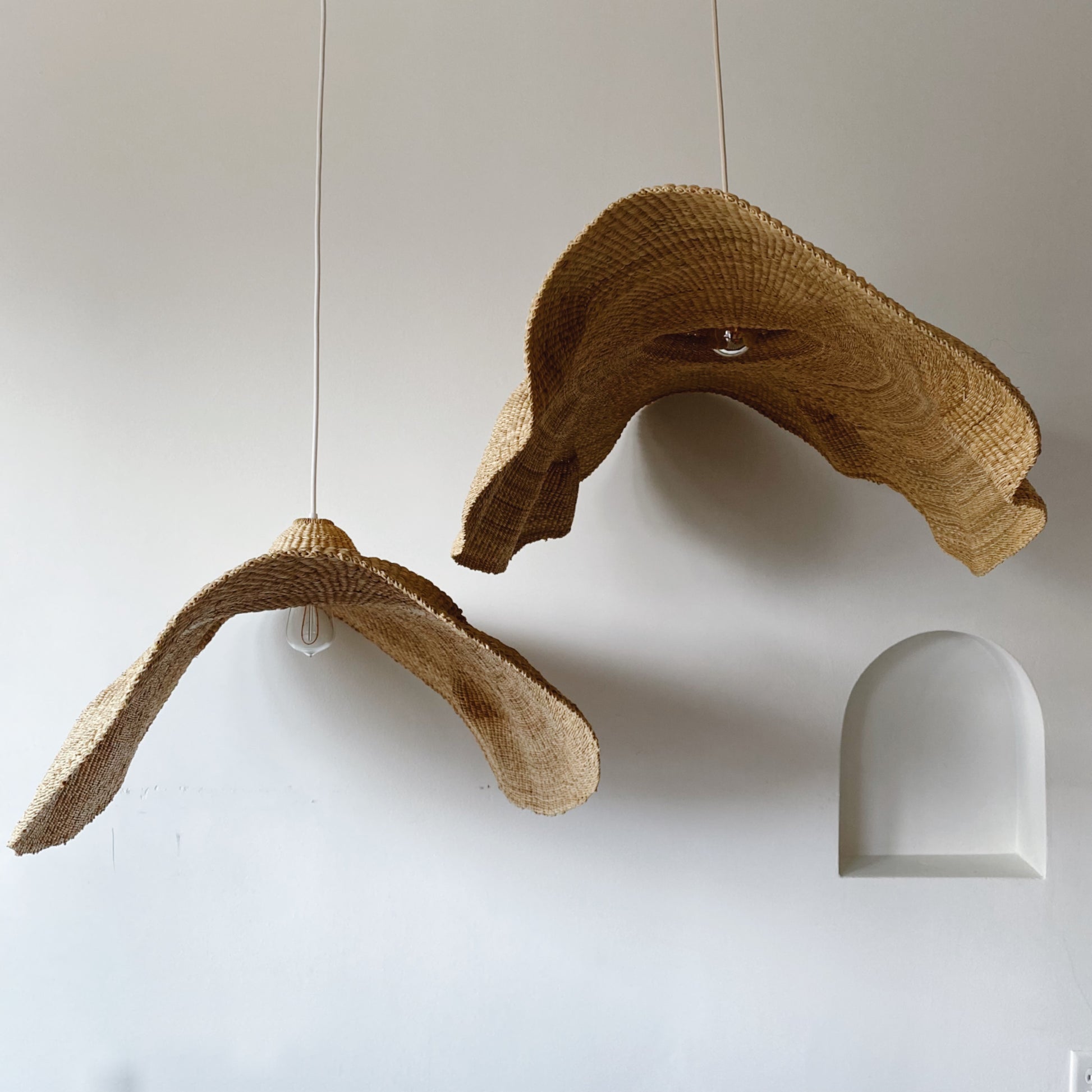 Two woven light shades, handwoven from sustainable elephant grass in Ghana. Their wide and floating shape are striking in any living space, especially in bedrooms or over dining tables.