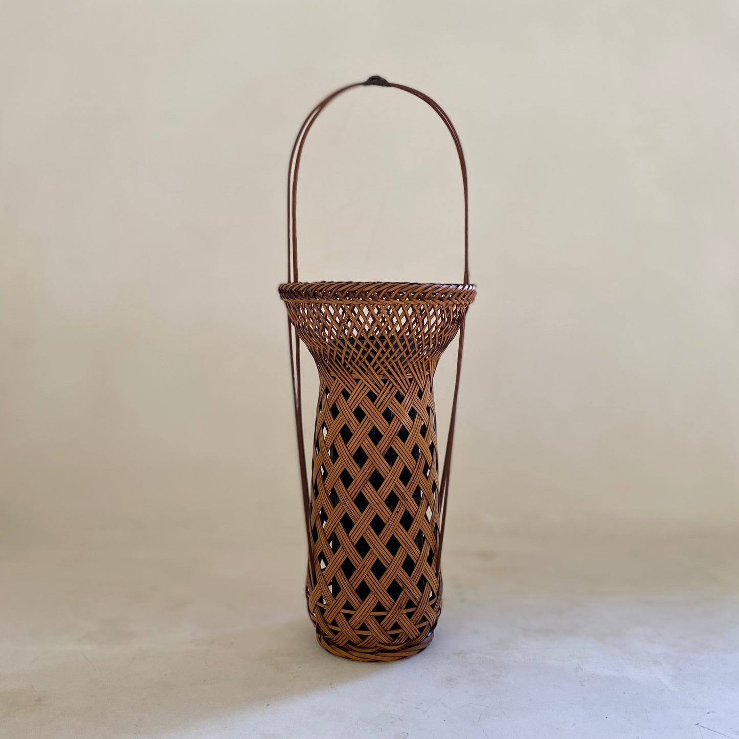 A vintage Japanese Ikebana (flower arrangement) basket with handle. Woven by hand in Japan from caramel colored bamboo. Circa 1950.