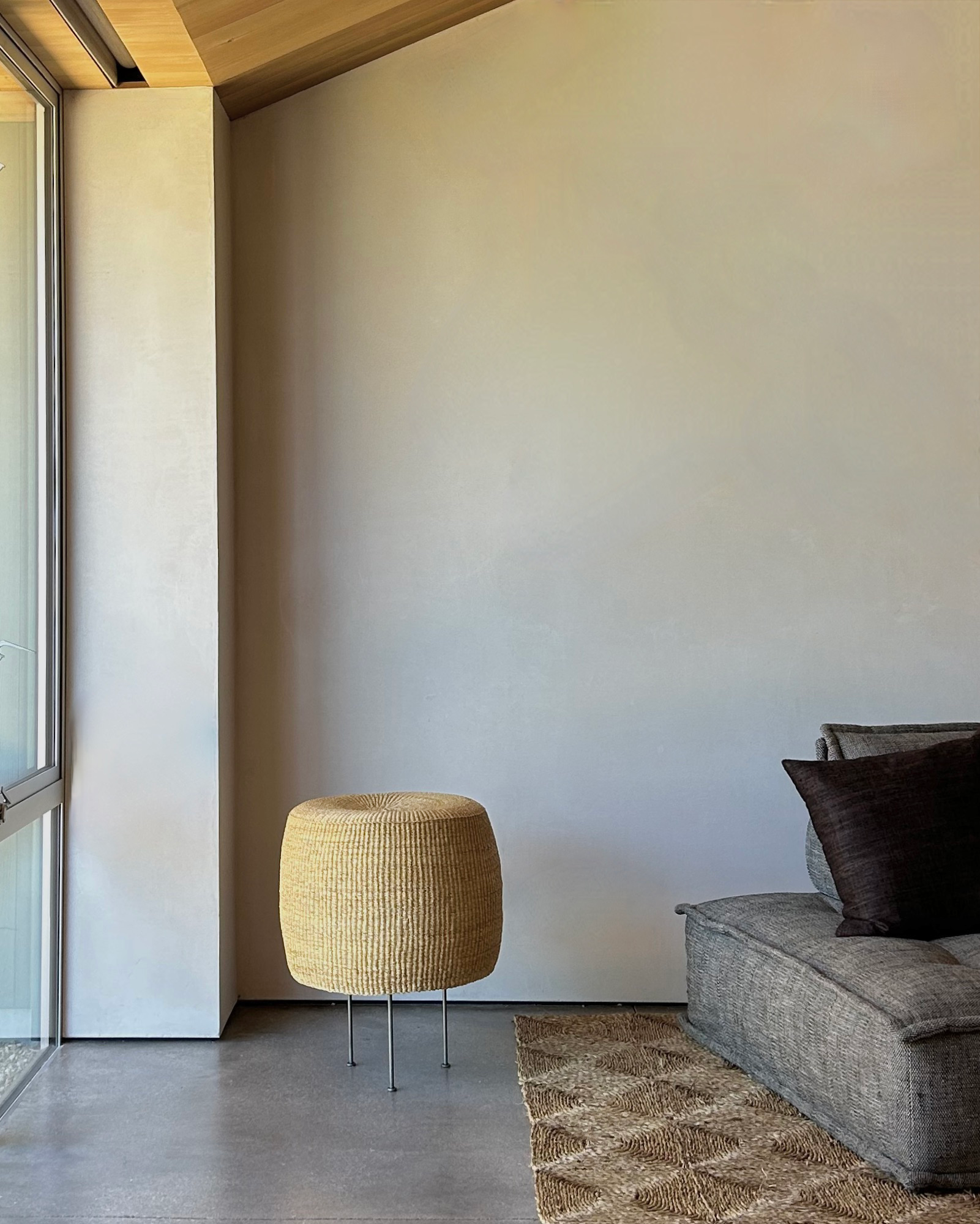 Woven floor lamp with steel tripod base in a neutral modern interior