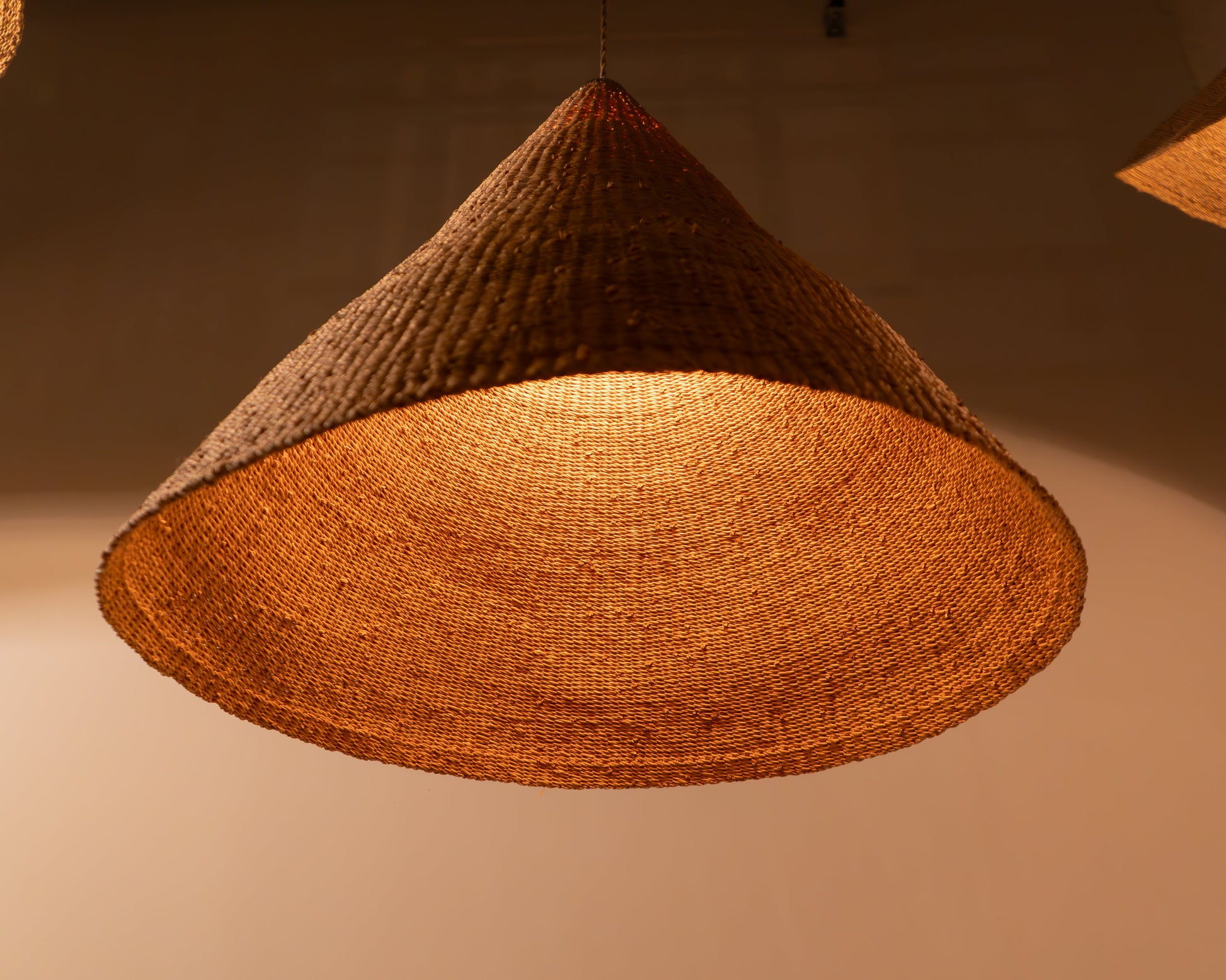 Woven pendant light with a warm glow on a neutral background