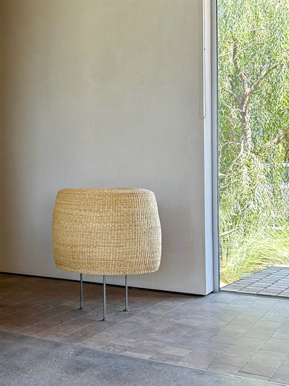 Woven floor lamp with steel tripod base in a modern indoor setting