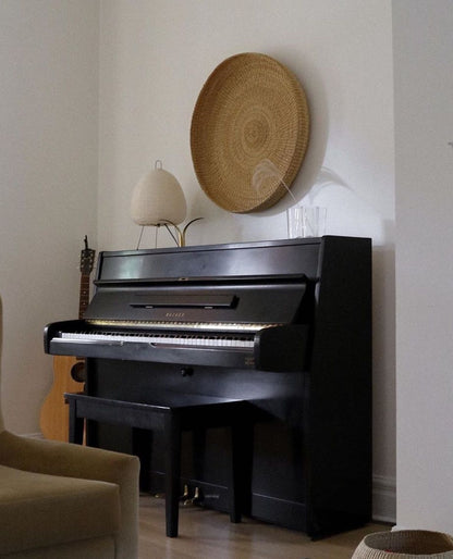 Handwoven round tray above a piano, made from sustainable natural grass.