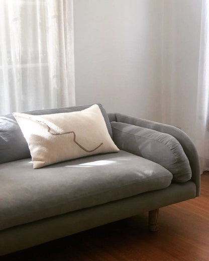 Cream rectangular cushion on a sofa, with a single brown squiggle line pattern.