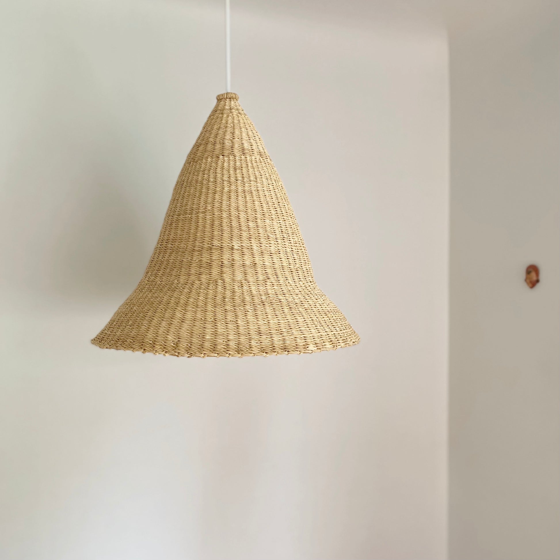 Witches Hat light shade is handwoven from sustainable materials in Ghana. They are a steep cone shape. Their steep cone shape casts a downward light, ideal for spaces that call for a more direct light source.