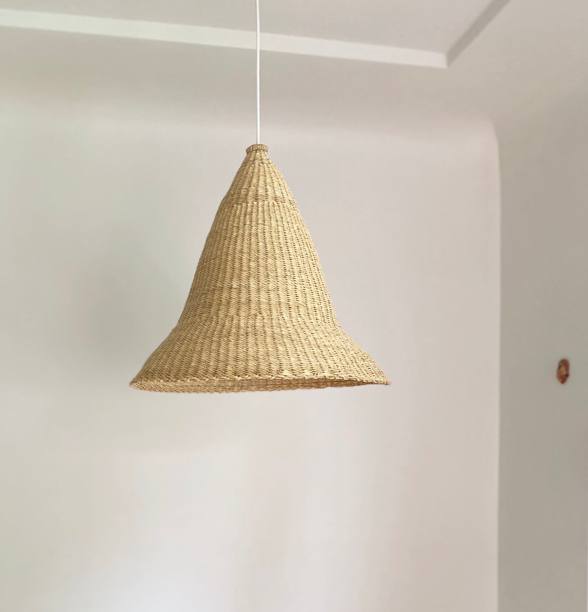 Witches Hat light shade is handwoven from sustainable materials in Ghana. They are a step cone shape. Their steep cone shape casts a downward light, ideal for spaces that call for a more direct light source.