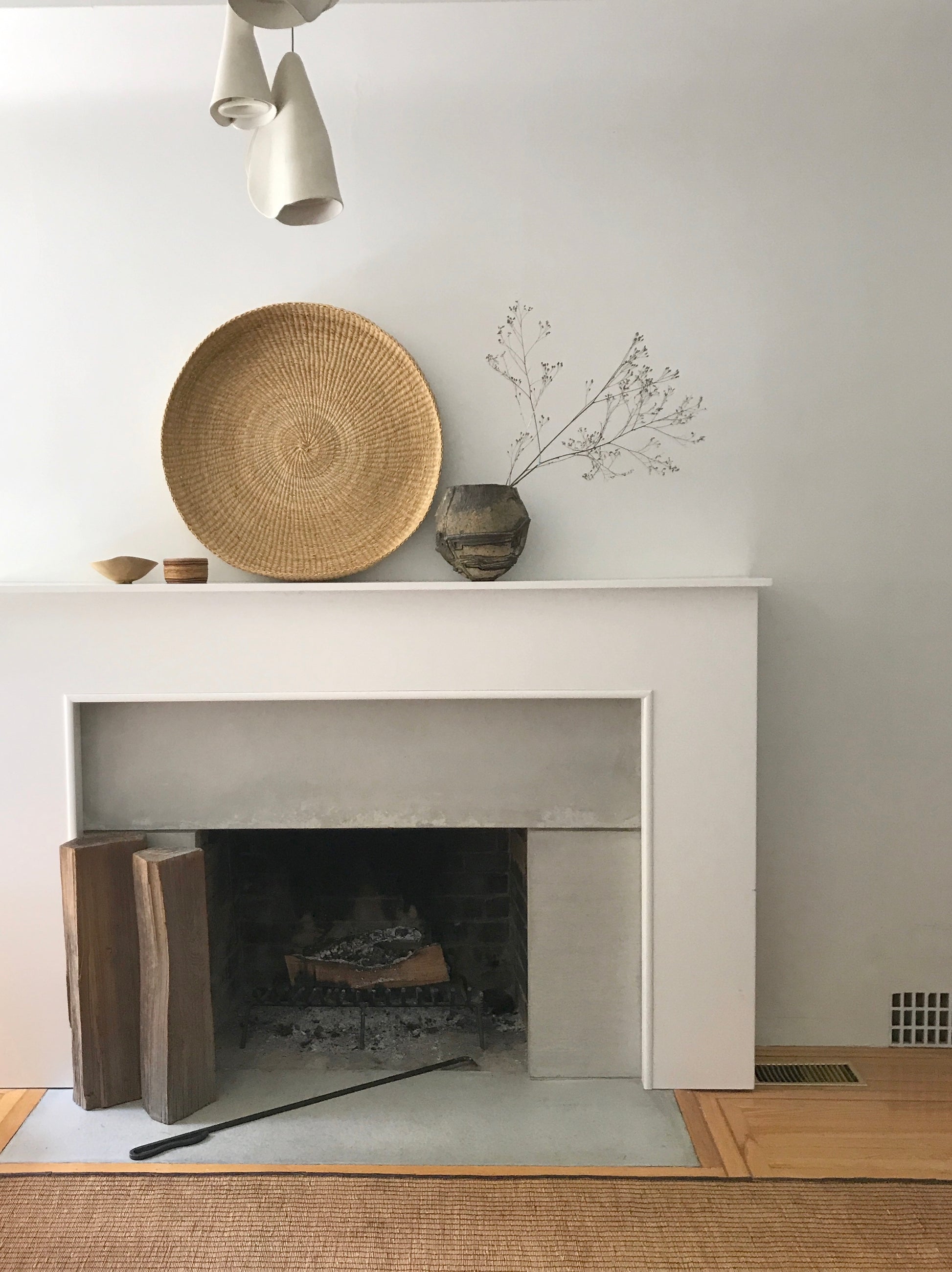Handwoven round tray made from sustainable natural grass, placed on fireplace.